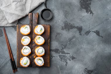 Suşi rulo geyşası, ateşte kavrulmuş somon balığı, levrek, karides, avokado seti, gri taştan arka planda, üst manzara düz, metin için metin alanı ve boşluğu olan.