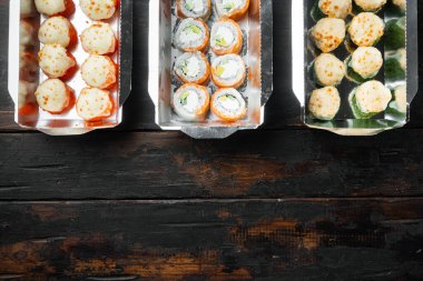 Suşi ruloları eski koyu ahşap masa arka planında, suşi ruloları seti, üst görünüm düz, metin için metin alanı ve yeri ile