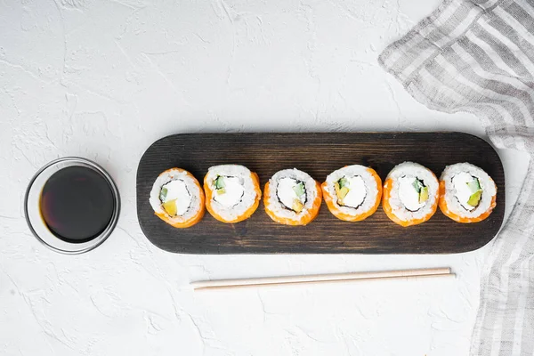 Suşi rulo somon ve ton balığının yemek çubukları beyaz taş zemin üzerinde, üst görünüm düz, kopyalanma alanı ve metin için boşluk