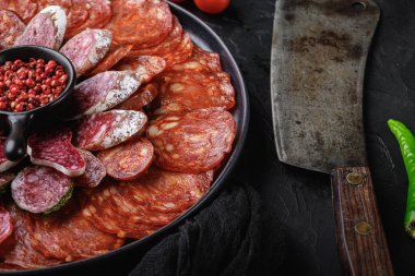 Geleneksel İspanyol mezelerinden yapılmış bir tabak et. Chorizo, salchichon, longaniza ve siyah desenli arka plan üzerine fuet.