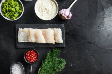 Organik balık ve patates kızartması hamur hamuru üzerine çiğ balık filetosu, patates, tartar sosu, nane lapası bezelyesi, limon, soğan, nane, sarımsak, tuz, siyah taş zemin üzerinde kırmızı biber.