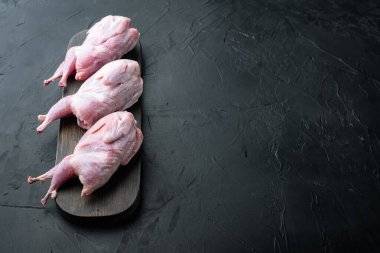 Taze organik bıldırcın eti, fotokopi alanı ile siyah desenli arka planda.