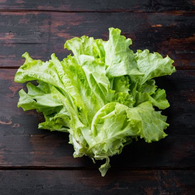 Çiğ organik yeşil, meşe marulu, koyu ahşap arka planda.