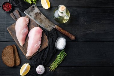 Çiğ tavuk filetosu, içinde kasap bıçağı ve siyah ahşap masa, düz yerde fotokopi alanı var.