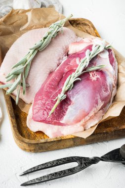 Çiğ pişmemiş kümes hayvanı eti. Ördek göğsü seti, bitkiler ve malzemelerle, tahta tepside, beyaz taş arka planda.