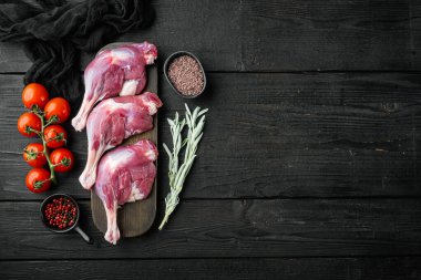 Çiğ et, ördek bacağı seti, siyah ahşap masa arkaplanı, telif alanı ve metin için yeri olan üst görünüm düzlüğü.