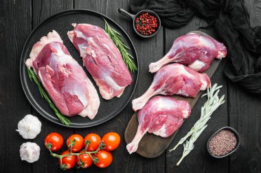 Ördek eti butları tavuk göğsü çiğ menü konseptini karıştırır. Bitkiler ve malzemelerle servis edilir. Siyah ahşap masa arka planında.