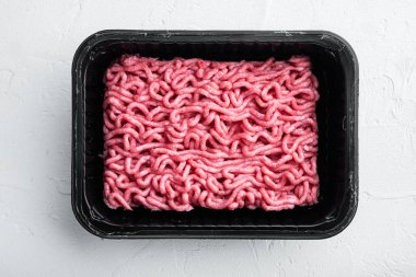 Plastik tepside kıyma, beyaz taş zemin, üst manzara, düz yatış.