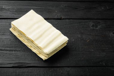 Siyah ahşap masa zemininde lazanya hamuru çarşafları, metin için kopyalama alanı