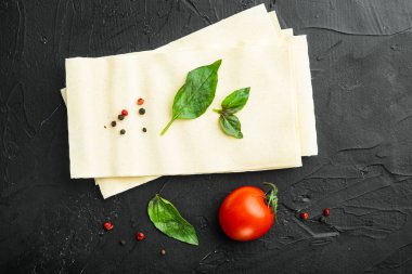 Kurutulmamış lazanya makarna seti, baharat ve otlu, siyah taş arka planda, üst görünümde, düz yerde