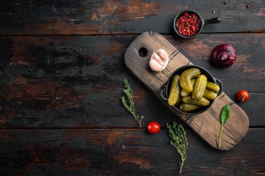 Ev yapımı konserve. Terbiye edilmiş salatalık turşusu seti, eski koyu ahşap masa arkaplanı, üst görünüm düz, metin kopyalanacak yeri var.