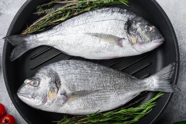 Çiğ deniz kepeği ya da ızgara tavada çiğ balık. Gri beyaz desenli arka plan, üst manzara, seçici odak.