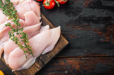 Çiğ organik tavuk göğsü, eski koyu ahşap masa arkaplanı, üst görünüm düz metin alanı için fotokopi alanı ile