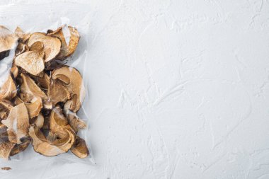 Kurumuş porcini mantarlar seti, beyaz arka planda, plastik pakette, üst görünüm düz yerde, metin kopyalama alanı için yer var