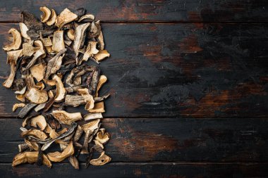 Vahşi organik kurutulmuş porcini mantar seti, eski koyu ahşap masa arkaplanı, üst görünüm düz, metin kopyalanacak yeri var.