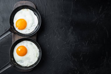 Yağda pişmiş yumurta, domuz yağı, ekmek ve yeşil tüy dökme demir tavada, siyah arka planda, üst görünüm düz, metin kopyalanacak yer