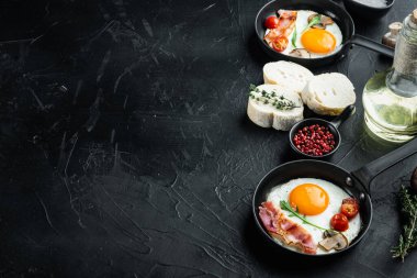 Domuz pastırması ve sebzeli sahanda yumurta, dökme demir kızartma tavasında, siyah arka planda, metin kopyalama alanı ile birlikte.