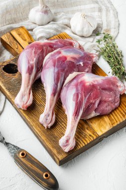 Otlar ve malzemelerle ahşap kesme tahtasına, beyaz taş zemin üzerine ördek bacakları dizilmiş.