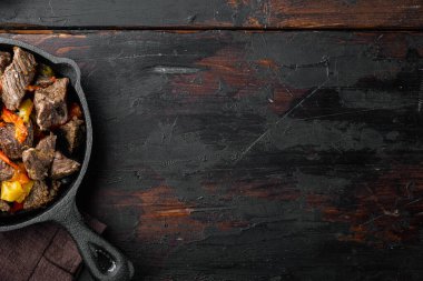 Moğol bifteği, soya sosunda pişirilmiş sığır eti, dökme demir kızartma tavası, eski siyah ahşap masa, üst düz görünüm yatağı, metin için kopya alanı