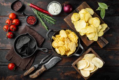 Değişik patates cipsleri seti, eski koyu ahşap masa, üst manzara düz yatıyordu