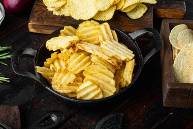 Farklı patates cipsleri, eski, siyah ahşap masa üzerinde.