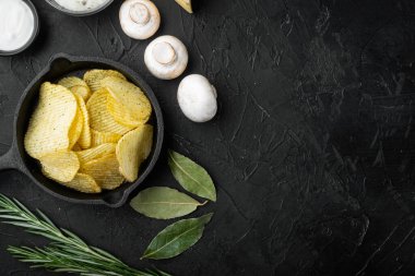 Peynir ve soğanlı ev yapımı patates cipsi, siyah taştan arka planda, en üstteki düz yerde, metin için kopyalama alanı var.