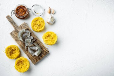 Beyaz taş yüzeyinde deniz ürünleri içerikli erişteler, üst görünüm düz, metin için kopyalama alanı var.