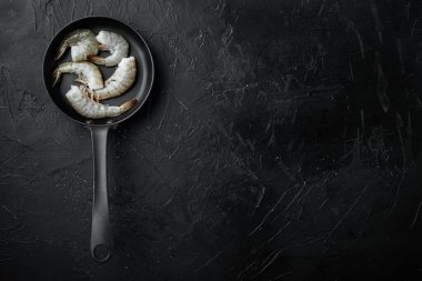 Çiğ taze karides seti, siyah taş zemin üzerinde karides, üst görünüm düz, metin için kopyalama alanı ile