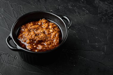 Kırmızı pesto italyan sosu, kasede, siyah taş zemin üzerinde, metin için kopya alanı ile