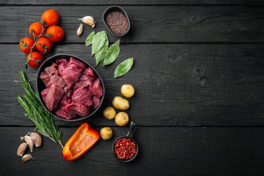 Çiğ sığır eti ve patates, siyah ahşap arka planda, üst görünüm düz, metin için kopyalama alanı ile