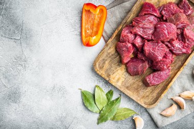 Biftek yahnisi ham bileşenleri, gri taş zemin üzerinde, üst görünüm düz yatay, metin için kopyalama alanı ile