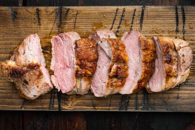 Izgara ördek eti fileto seti, ahşap servis tahtasının üzerinde, eski siyah ahşap masa arkasında.