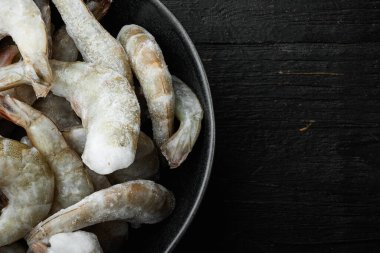 Donmuş çiğ kaplan karidesleri, karides seti, siyah ahşap arka planda, üst görünüm düz, metin için kopyalama alanı ile