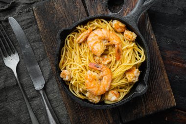 Deniz ürünleri spagettisi pesto hazır, dökme demir tavada, eski, siyah ahşap masada, düz manzaralı