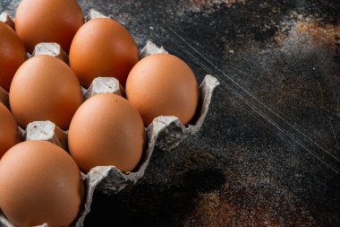 Kağıt yumurta kutusu seti üzerinde taze yumurtalar, eski koyu kırsal arka planda, metin kopyalama alanı ile