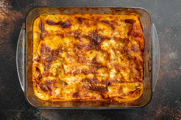 Geleneksel lazanya, üzerine fesleğen yaprakları serpiştirilmiş kıymalı bolonez sosu, eski, koyu kırsal arka planda, üst görünümde, düz yerde.