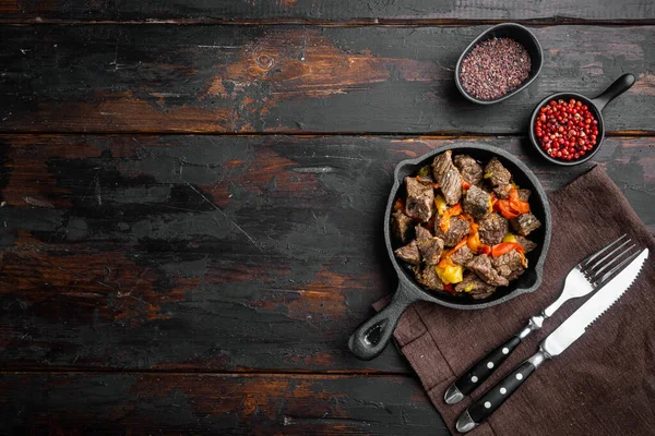 Sığır güveci goulash - rustik stil seti, dökme demir kızartma tavası, eski koyu ahşap masa üzerinde, üst düz görünüm yatağı, metin için metin alanı