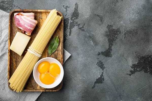 Ingredients for making pasta alla carbonara prosciutto, raw pasta set, on gray stone background, top view flat lay, with copy space for text