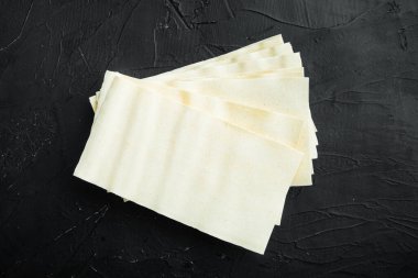 Pişmemiş lazanya çarşafları, siyah taş zemin üzerinde, üst görünüm, düz yatış