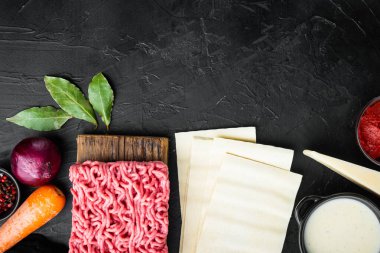 Lazanya pişirme konsepti. İçindekiler, lazanya çarşafları, fesleğen, kiraz domatesleri, parmesan, sarımsak, biber seti, siyah taş zemin, üst görünüm, düz yatış, metin için kopya alanı