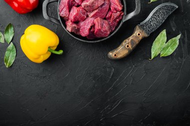 Çiğ et yahni için doğranır tatlı dolma biber ile, dökme demir tavada, siyah taş zemin üzerinde, üst görünüm düz, metin için kopyalama alanı ile