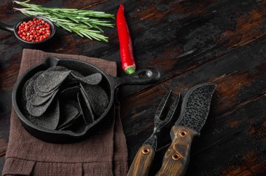 Siyah gevrek patates cipsi seti, eski, siyah ahşap masa üzerinde.