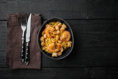 Pesto soslu ve karidesli leziz spagetti, siyah ahşap arka planda, en üstteki düz yerde, metin için fotokopi alanı var.
