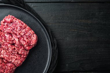 Kıymalı biftek, siyah ahşap masa arkaplanı, üst görünüm düz metin için kopyalama alanı ile yatar