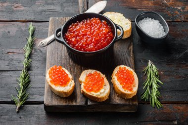 Kırmızı havyarlı kanepe tostları, eski siyah ahşap masa arka planında