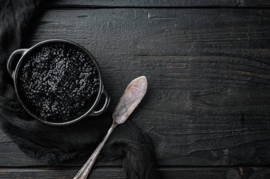 Siyah mersin balığı havyarı kasede, siyah ahşap masa zemininde, en üstteki daire metin için fotokopi alanı ile yatıyordu.