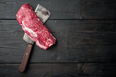 Taze ve çiğ et. Eski kasap bıçağı ile sığır filetosu biftek seti, siyah ahşap masa arka planı, üst düz görünüm, metin için metin alanı