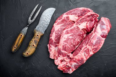 Çiğ mermer et seti, pirzola kesimi, siyah taş arka planda, üst manzara düz.