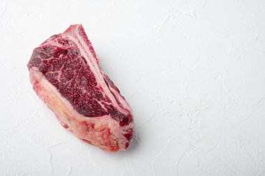 Çiğ et, kurutulmuş mermer ya da kemik biftek seti üzerinde çizgili beyaz taş arka planda, metin için kopyalama alanı ile