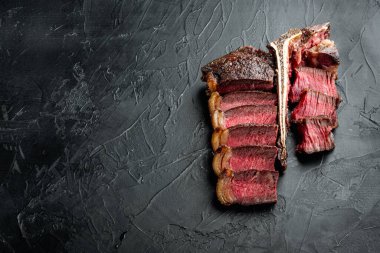 Orta pişmiş biftek seti, kemik ya da biftek kesimi, siyah taştan arka planda, düz manzaralı, metin için fotokopi alanı var.
